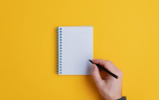 Male hand about to write in blank notebook